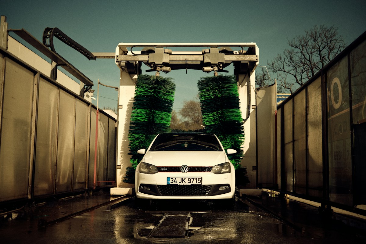 A white car driving into an automated wash bay